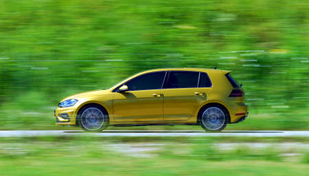 A panning shot of a speeding yelow carの写真素材
