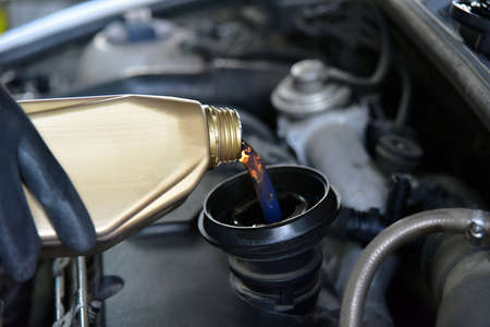 From cans of oil pouring oil in car engine