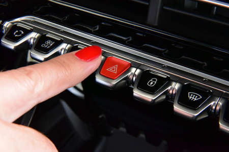 Woman pressing red triangle car hazard warning button
