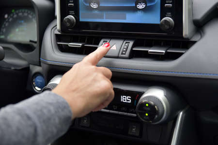 Female pressing red triangle car hazard warning button
