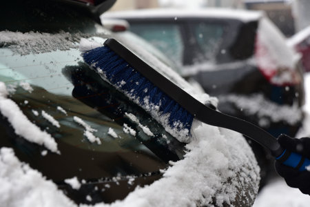Removing snow from the car window with a brushの写真素材