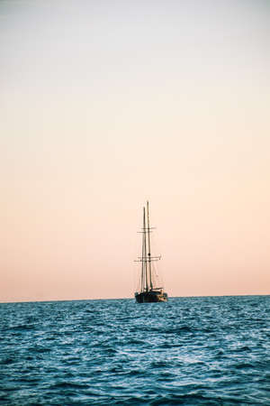 Sailing boat sailing in the middle of the sea during sunsetの写真素材