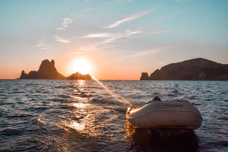 View from the back of a sailboat of the sunset with the dinghy