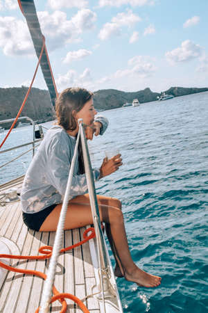 Young woman drinking coffee on a sailboat