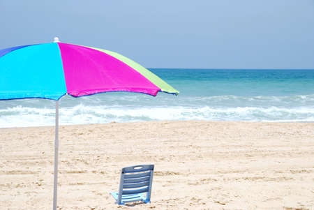 Colored beach umbrella and empty chair on sea coast.の写真素材