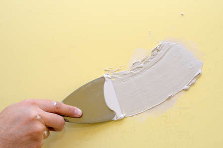 Hand with putty knife repair damaged wallの写真素材