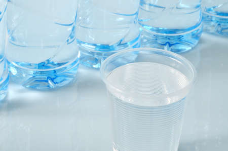 Plastic cup and bottles of water close-up.の写真素材