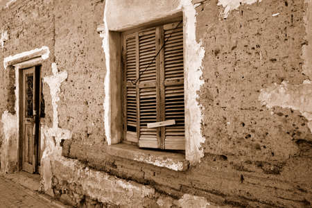 Fragment wall of old abandoned building with cracked door and window. Sepiaの写真素材
