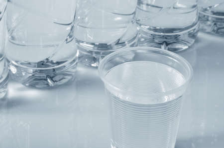 Plastic cup and bottles of water close-up. Monochromeの写真素材