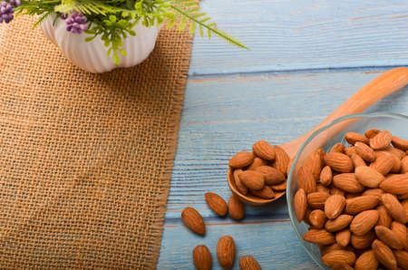 Almond nuts in a glass bowl on a wooden background. Selective focus.の写真素材