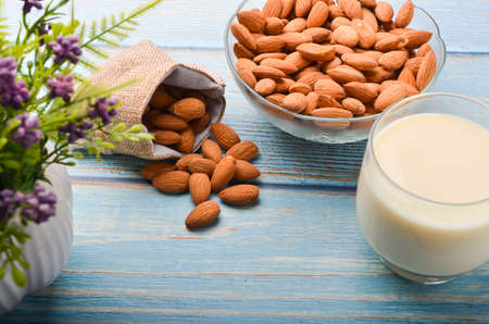 Close up view of healthy almond milk in drinking glass with seed in bowl on wooden background. Selective focus.の写真素材