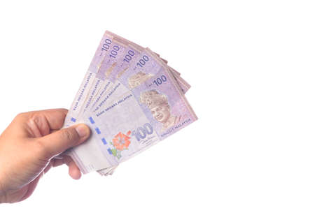 Hand showing 100 Ringgit Malaysia (MYR) money with over white  background and selective focus.