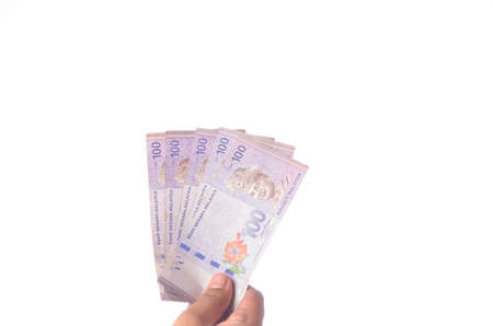 Hand showing 100 Ringgit Malaysia (MYR) money with over white  background and selective focus.