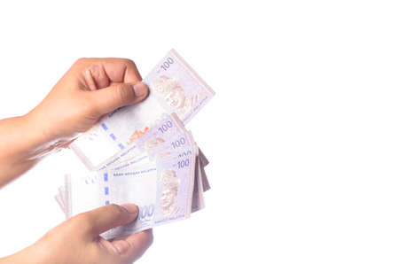Hand showing 100 Ringgit Malaysia (MYR) money with over white  background and selective focus.