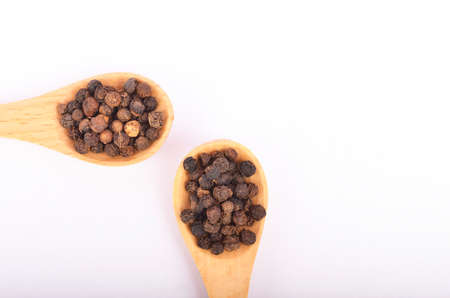 Black peppers on wooden spoon isolated on white background. Selective focus.の写真素材