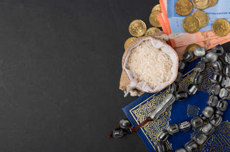 Coins, rosary, Holy Quran and rice in the sack. Zakat concept. Zakat is a form of alm-giving as a...