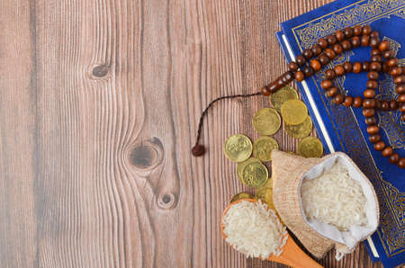 Coins, rosary, Holy Quran and rice in the sack. Zakat concept. Zakat is a form of alm-giving as a religious obligation or tax. Large Arab word right method to read correctly.の写真素材