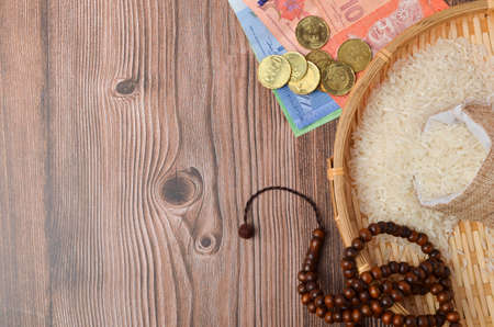 Coins, rosary, Holy Quran and rice in the sack. Zakat concept. Zakat is a form of alm-giving as a...