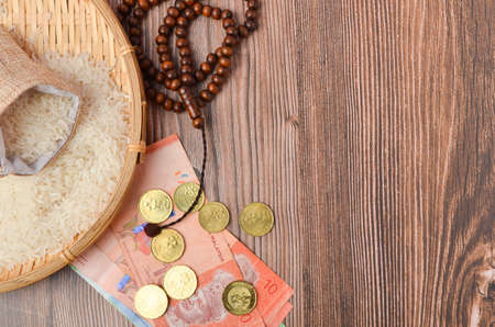 Coins, rosary, Holy Quran and rice in the sack. Zakat concept. Zakat is a form of alm-giving as a religious obligation or tax. Large Arab word right method to read correctly.の写真素材