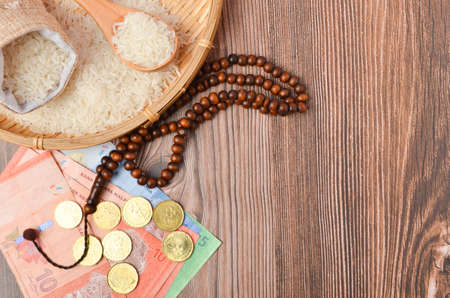 Coins, rosary, Holy Quran and rice in the sack. Zakat concept. Zakat is a form of alm-giving as a...