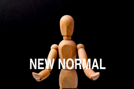 Wooden figure with text "NEW NORMAL" on black background. Selective focus.の写真素材