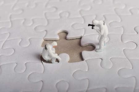 Miniature people ; Crime Scene Investigation with missing jigsaw puzzle. Selective focus.