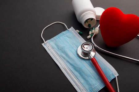 Face mask, red heart and stethoscope on black background. health concept.の写真素材