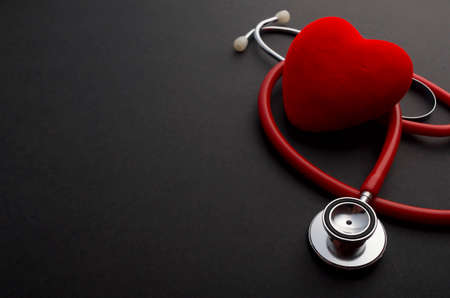 Face mask, red heart and stethoscope on black background. health concept.