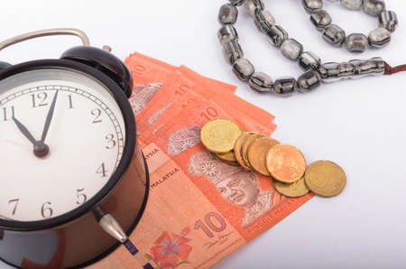 Rosary, coins in a gunny sack and alarm clock. Islamic banking/finance concept on over white...