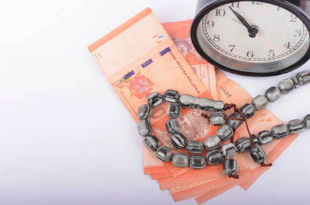 Rosary, coins in a gunny sack and alarm clock. Islamic banking/finance concept on over white...