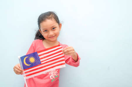 Malay girl holding Malaysia flag. Malaysia independence concept. Selective focus.の写真素材