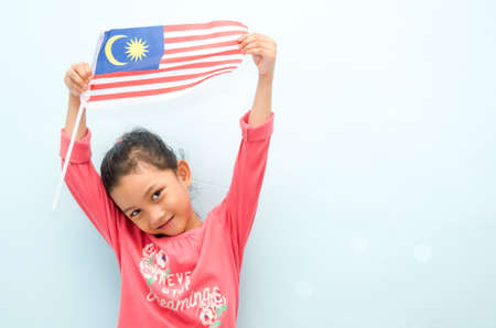 Malay girl holding Malaysia flag. Malaysia independence concept. Selective focus.の写真素材