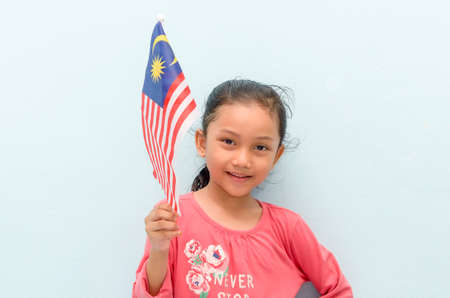 Malay girl holding Malaysia flag. Malaysia independence concept. Selective focus.の写真素材