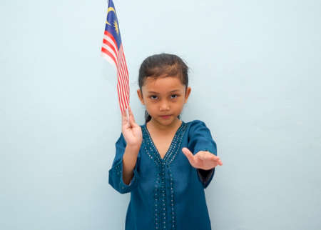 Malay girl holding Malaysia flag. Malaysia independence concept. Selective focus.の写真素材