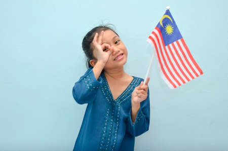 Malay girl holding Malaysia flag. Malaysia independence concept. Selective focus.の写真素材