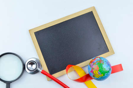The concept of 'World Hepatitis Day' with yellow and red ribbon, world globe, stethoscope, syringe, magnifying glass and black board for your text.の写真素材