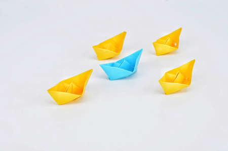 Leadership concept with a blue paper ship leading among yelllow shipsの写真素材