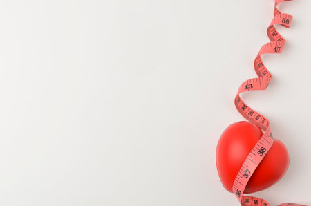 Red heart with measure tape on white background. Healthy concept.の写真素材