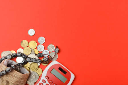 Rosary with coins in a gunny sack and calculator on red background. Islamic banking or financing...
