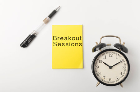 Top view of a alarm clock and pen with written Breakout Sessions on white background. Selective...