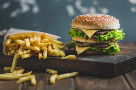 Burger with potatoes and dark beer on a wooden Board on a blue-gray backgroundの写真素材