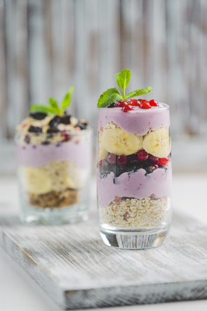 granola in a glass with yogurt and berries on a white backgroundの写真素材