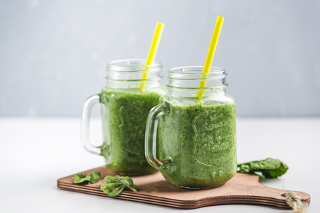 Green smoothie with spinach, Apple, cucumber and coconut milk on white background. Side view. Vegetarian drink. Healthy diet.の写真素材