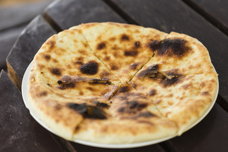 National Georgian dish khachapuri megrelian with cheese on a dark wooden background top view.