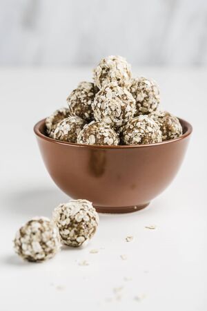 Energy balls of nuts, oats and dates in a brown Cup, closeup, on white background with copyspace isolated. Healthy food. Raw dessert.の写真素材