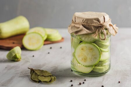 Fermented zucchini in a jar of spices on a light background close-up with copyspace. Harvesting vegetables for healthy food.の写真素材