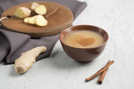 Tea masala in a Cup on the plate with the winter spices of cinnamon and ginger on a light background side view closeup with copyspaceの写真素材