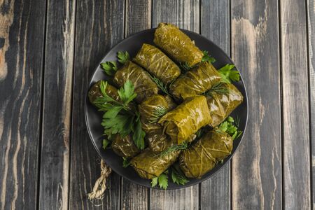 Delicious stuffed grape leaves (traditional doom Mediterranean cuisine Dolma) on a black plate with fresh cilantro and dill on dark wooden background top view with copyspaceの写真素材