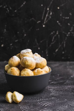 Eclairs with cottage cheese in a black bowl on a dark background closeup with copyspace. Low key. Homemade cake.の写真素材