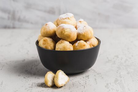 Eclairs with cottage cheese in a black bowl on a light background closeup with copyspace. Homemade cake.の写真素材